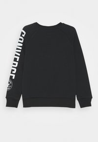 Felpa nera con il testo "CONVERSE" bianco che scorre lungo la manica sinistra e un logo sulla manica destra. Presenta un collo girocollo e polsini a costine.