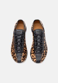 Sorte og leopardmønstrede sneakers med en glat tekstur, der har snørebånd og læderdetaljer, designet til afslappet brug.