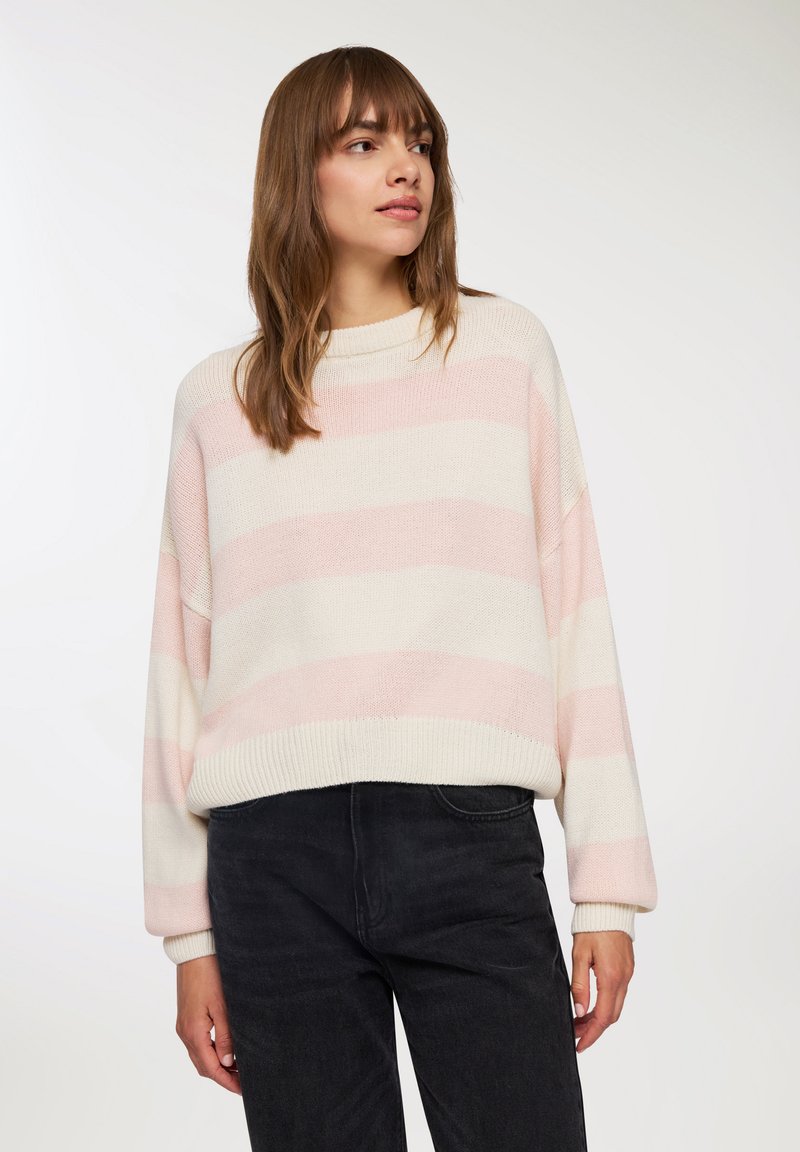 Sweter dzianinowy z poziomymi paskami w jasnym różu i kremowym. Lekko oversize, z wysokim kołnierzem oraz ściągaczami przy mankietach i u dołu.