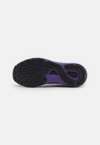 Semelle de chaussure de course violette et noire avec un motif de semelle texturé et le logo Under Armour au centre, isolée sur fond blanc.