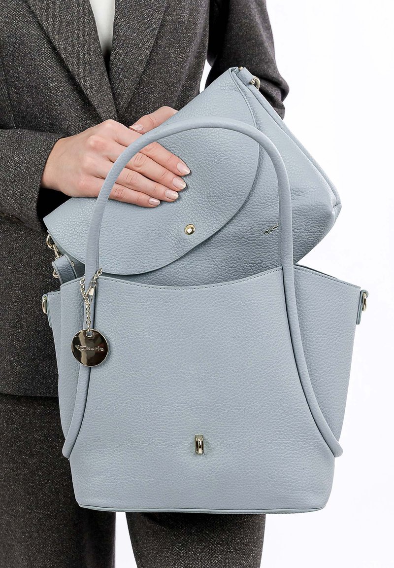 Sac à main en cuir gris clair avec une surface texturée, comprenant une pochette plus petite à l'intérieur. Agrémenté d'un charm en métal et d'un fermoir subtil.