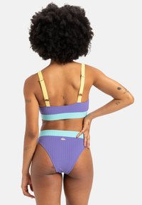 Purple ribbed bikini set with light blue and yellow accents. Features adjustable yellow straps and a high-waisted bottom design.