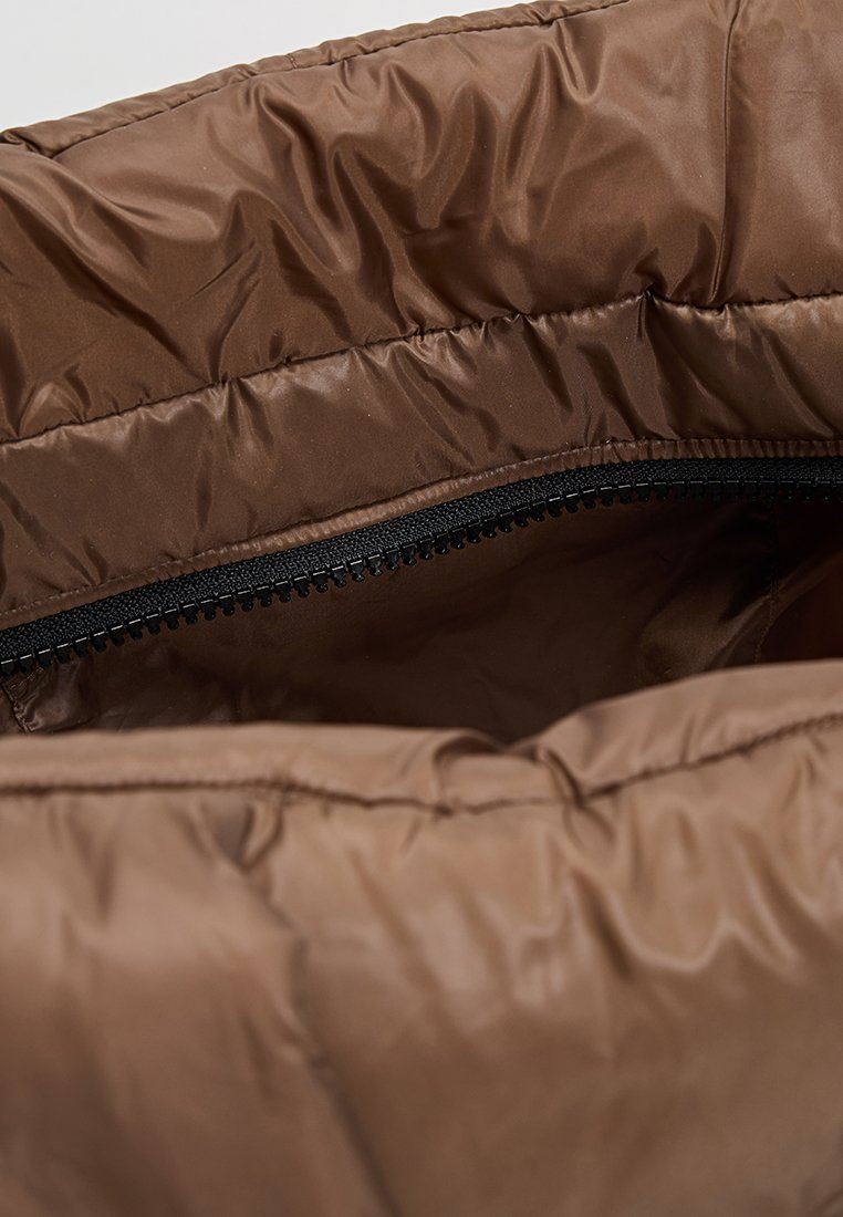 Braune Puffer-Tasche mit einer weichen, glänzenden Textur, ausgestattet mit einem schwarzen Reißverschluss entlang der oberen Kante für den Verschluss. Das Innenfutter ist in passendem Braun gehalten.