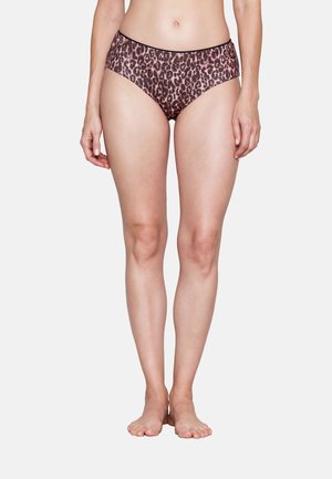 Frau trägt Leopardenmuster-Hipster-Unterwäsche und steht barfuß vor einem schlichten weißen Hintergrund.