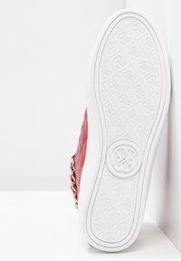 Red quilted shoe with gold chain accents and white rubber sole. The sole features a textured pattern and embossed logo in the center.