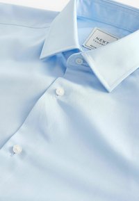 Világoskék gombos ing sima anyagból, széles gallérral, fehér gombokkal és "Next Tailored" felirattal ellátott címkével.