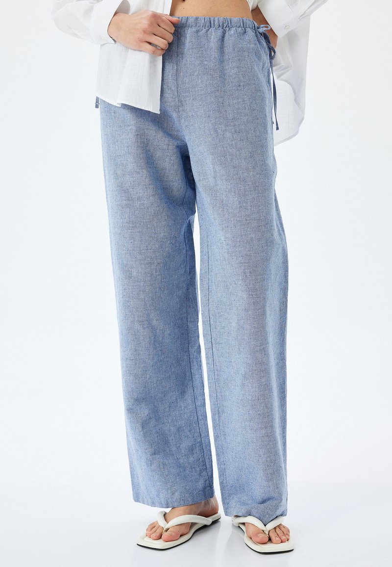 Lichtblauwe, wijde broek van geweven stof met een elastische tailleband en trekkoord. Kenmerkt zich door een gladde textuur en minimale stiknaden.