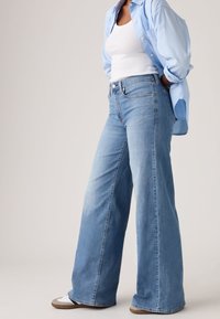 Φαρδιά τζιν παντελόνια σε ανοιχτό μπλε χρώμα από denim, με κλασικό σχέδιο πέντε τσεπών και εφαρμοστή μέση. Λείο υλικό, με ελαφρώς ξεθωριασμένη όψη.