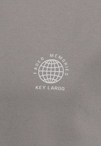 T-shirt in cotone grigio con una grafica bianca di un globo, con "Faded Memories" sopra e "Key Largo" sotto, centrata sul petto.