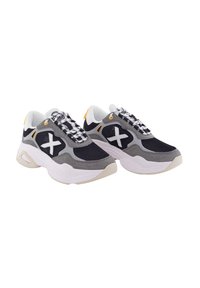 Zapatillas de malla negras y grises con una suela blanca gruesa. Presentan un gran logo blanco en forma de 'X', tela texturizada y un diseño de cordones con patrón.
