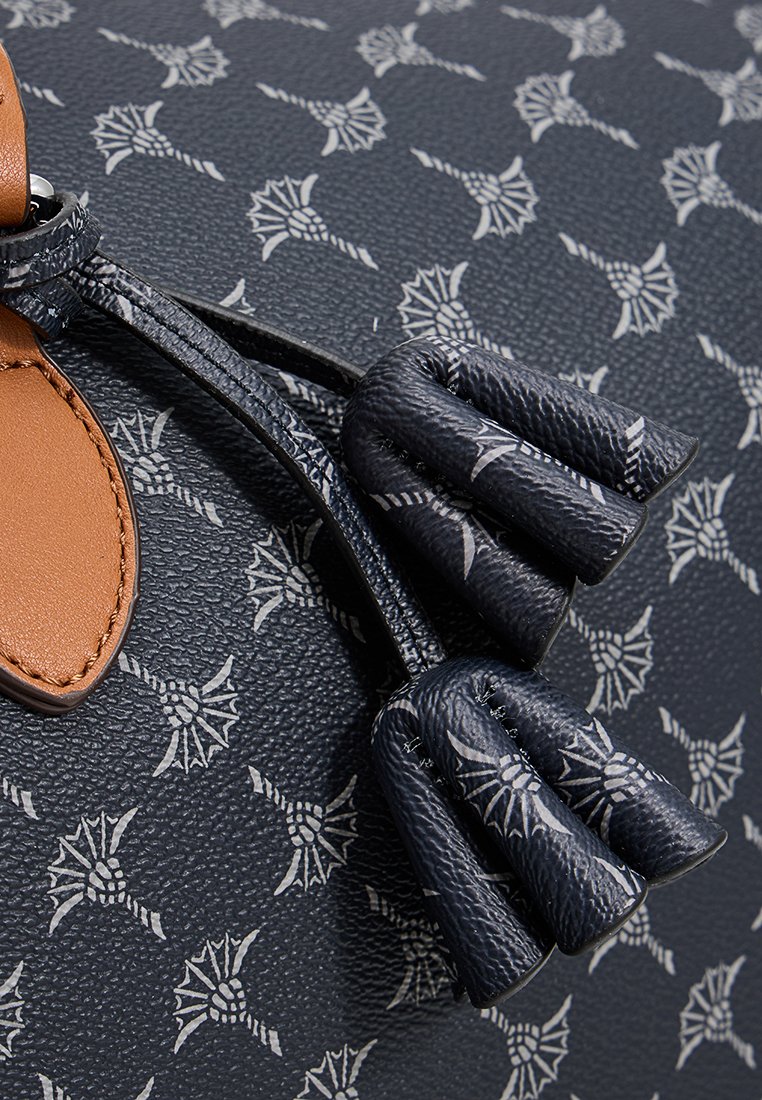 Dunkelblaue strukturierten Lederhandtasche mit einem sich wiederholenden weißen Muster, versehen mit einem braunen Lederakzent und mehreren dunklen Quasten.