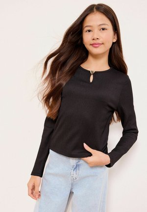 Must pikkade varrukatega ülaosa soonilise tekstuuriga, millel on südamekujulise detailiga ava. Kombineeritud helesiniste teksapükstega.