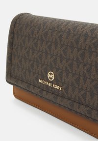 Brun mønstrede pung med Michael Kors-logoen i guld. Materialet er tekstureret med en glat brun base og guld hardware-accenter.