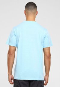 T-shirt en coton bleu clair, manches courtes, col rond, texture lisse, coupe standard, détails de couture visibles à l'ourlet.
