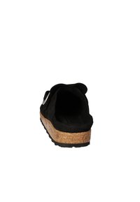 Chaussure noire en suède à enfiler avec une semelle en liège, présentant un talon légèrement surélevé et une ouverture arrondie. Accent en métal près de l'arrière.