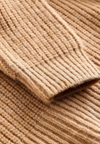 Geribbeld gebreide trui in een warme bruin tint, gemaakt van zacht materiaal met een gestructureerd oppervlak, met omgeslagen randen en een comfortabele uitstraling.