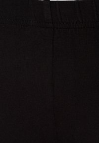 Leggings noirs en tissu extensible mélangé de coton. Présentent une texture côtelée, une taille élastique et aucun motif ou design visible.