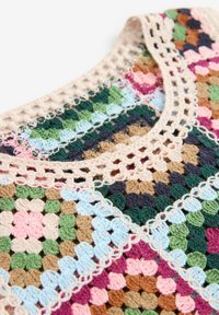 Vêtement au crochet avec des motifs granny square multicolores en vert, bleu, rose, marron et beige, assemblés avec un bord en dentelle beige autour de l'encolure.