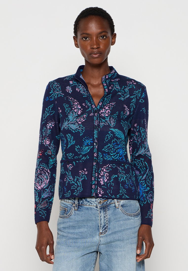 Gilet marine avec motifs floraux en rose et teal, fermeture éclair, manches longues et col montant. Matière en tricot douce.