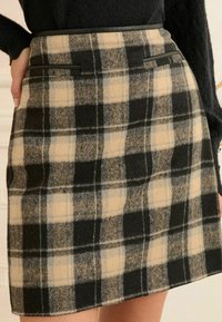 Fustă din amestec de lână, cu un model în carouri negru, bej și gri, cu buzunare frontale și o croială dreaptă, având o textură netedă.