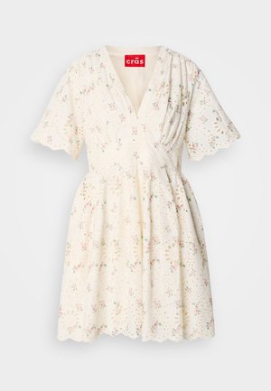 Vit klänning med ett blommönster i rosa och grönt, med v-ringning, korta ärmar och scalloped nederkant. Detalj av ögla tygstruktur.