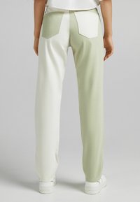 Pantalones de denim bicolor en verde claro y blanco con un corte relajado, que cuentan con dos bolsillos traseros y un diseño limpio y minimalista.