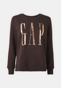 Sudadera marrón de manga larga y cuello redondo. Presenta letras metálicas doradas "GAP" en el frontal. Tejido suave y texturizado.
