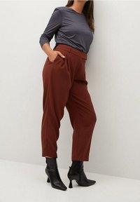 Mørkegrå langærmet top parret med høj talje, tapered bukser i rustfarve. Sættet har elegante sorte højhælede støvler.