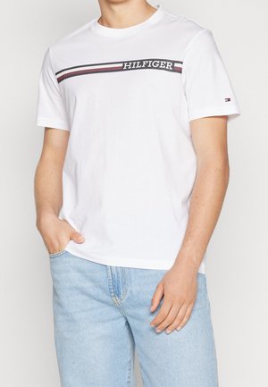 T-shirt en coton blanc avec des rayures horizontales bleu marine et rouge portant le texte "HILFIGER". Manches courtes, col rond et coupe décontractée.