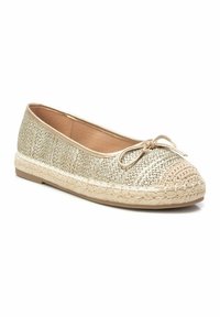 Zapato plano dorado tejido con una puntera redonda de ganchillo y un lazo decorativo en la parte delantera. Presenta una suela texturizada similar a paja.