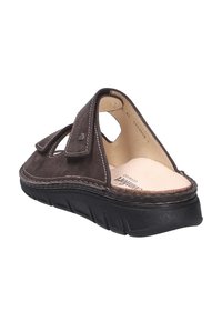 Sandalo in camoscio marrone con cinturino in Velcro. Design con caviglia aperta e suola in gomma nera testurizzata. Dettagli di cuciture marroni lungo il bordo.