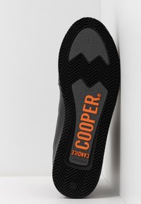 Suela de goma negra con banda de rodadura texturizada, destacando un prominente logo naranja "COOPER" y la inscripción "CANADICE". Tamaño marcado como 37.