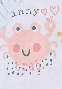 Lichtblauw kledingstuk met een gedrukt roze krabdesign, met grote ogen en blozende wangen, vergezeld van de tekst "grappige krab" in speelse typografie.
