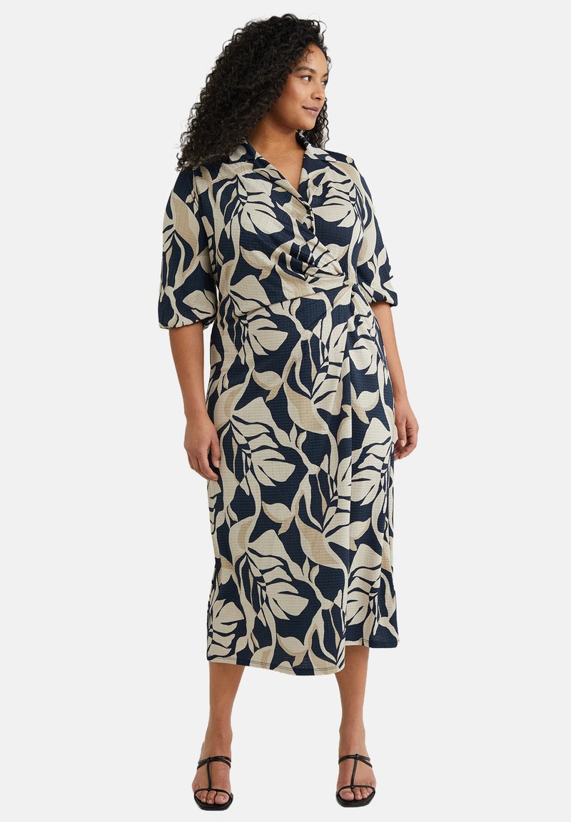 Patroonjurk met een marineblauwe basis en grote crèmekleurige bladvormen, kraaghals, korte mouwen en een getailleerde taille.