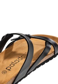 Sandale en cuir noir avec des lanières entrecroisées, semelle en liège et semelle texturée noire, taille 37, sur fond blanc.