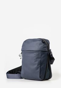 Compact dark gray crossbody bag with adjustable strap, zippered main compartment, and small front pocket, set against a white background.