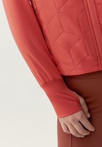 Koralli tilkkutakki, jossa on sileät, slim fit -pitkät hihat ja peukalon reiät, yhdistettynä matching-fitted alaosaan.