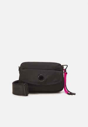 Petit sac bandoulière noir avec poche frontale à rabat, détail bouton rond, bandoulière réglable et tirette de fermeture éclair en cordon rose sur fond blanc.
