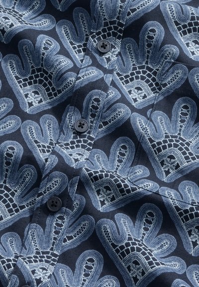 Tissu foncé avec des motifs répétés de couronnes bleu clair et des boutons noirs cousus sur le tissu, créant un effet texturé et en couches.