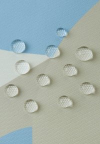 Transparente Wassertropfen auf einer strukturierten, hellen Oberfläche mit geometrischen Mustern in Blau und Creme, die Klarheit und Formvariationen zeigen.