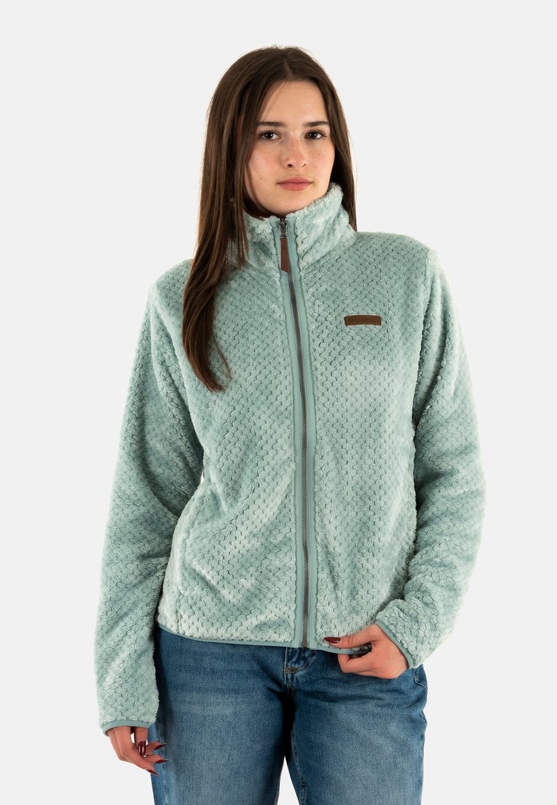 Chaqueta de forro polar verde claro con un alto cuello, patrón texturizado, cremallera frontal y una pequeña etiqueta marrón en el lado izquierdo del pecho.