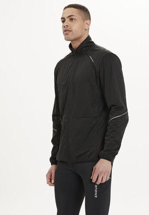 Schwarze, leichte Zip-Jacke mit hohem Kragen, ausgestattet mit reflektierenden Akzenten und einer Fronttasche, entworfen für sportliche Aktivitäten.