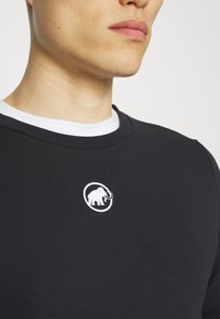 Felpa nera con un logo bianco rotondo che rappresenta un elefante al centro. Il materiale sembra liscio e ha un collo a giro.