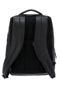 Mochila negra con respaldo de malla acolchada, asas de cuero ajustables y compartimentos con cremallera para almacenamiento. Textura suave con mínimo desgaste.