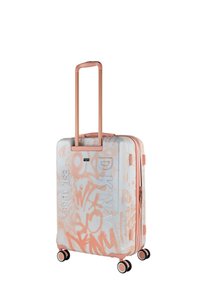 Maleta rígida con base blanca, estampados de grafiti en rosa y asa metálica en rosa dorado. Cuenta con cuatro ruedas para facilitar el movimiento.