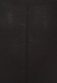 Leggings noirs en tissu extensible, présentant une texture lisse et un design simple. Pas de motifs visibles ni de détails matériels.