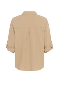 Beige overhemd met knopen, voorzien van een rugplooi, opgerolde mouwen en een kraag. Gemaakt van een zachte, gladde stof met een ontspannen pasvorm.