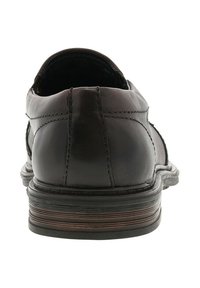 Chaussure en cuir noir avec un talon arrondi, texture lisse et détails cousus. Semelle large avec des rainures horizontales pour une adhérence et un soutien.