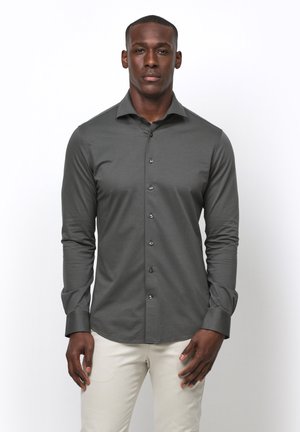 Camisa de botones de manga larga gris, hecha de una tela suave, con cuello estándar, tapeta frontal de botones y un diseño ajustado.