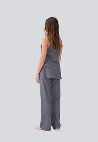 Ensemble gris en deux pièces comprenant un haut sans manches avec un dos superposé et un pantalon à jambe large. Le tissu présente un motif texturé.